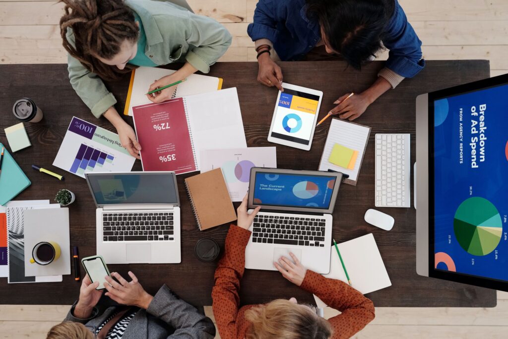 Team dat aan een marketingstrategie werkt op laptops, tablets en print-outs