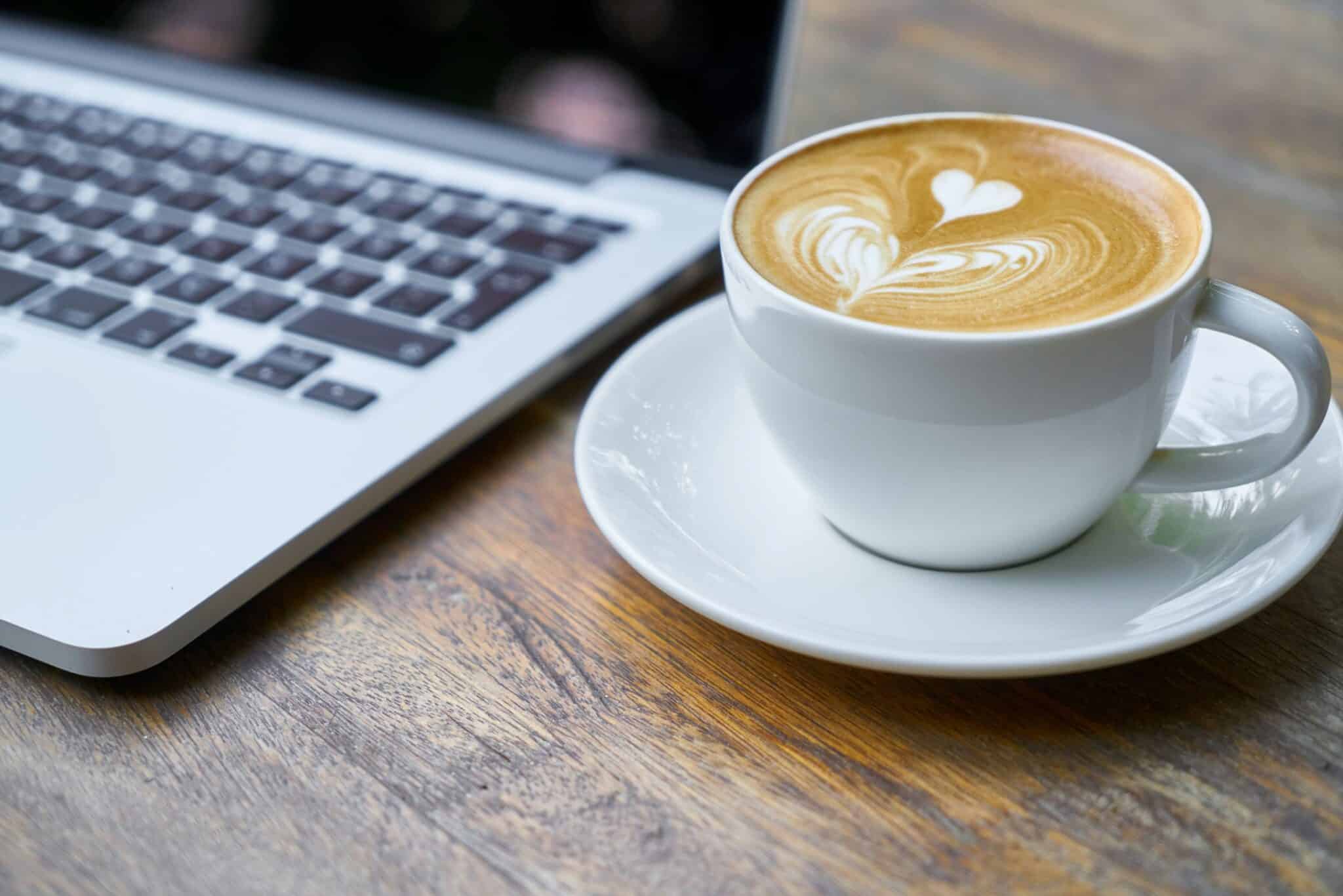 Close-up van een laptop naast een kop koffie, online marketing voor horeca