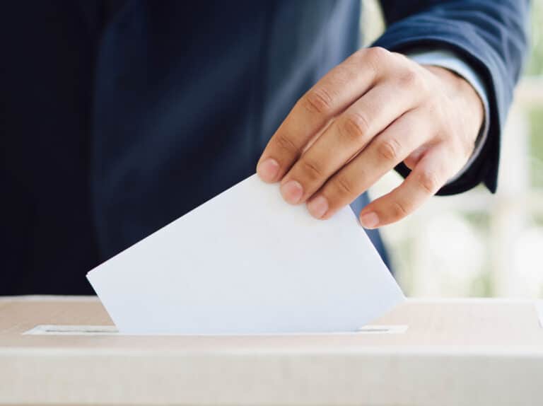 Hand die een stembrief in de stembus laat vallen na geslaagde online marketingplan voor politieke partij